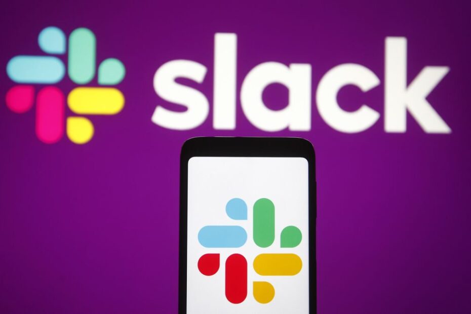 The slack logo on a mobile phone in front of a purple wall with the slack logo on it
