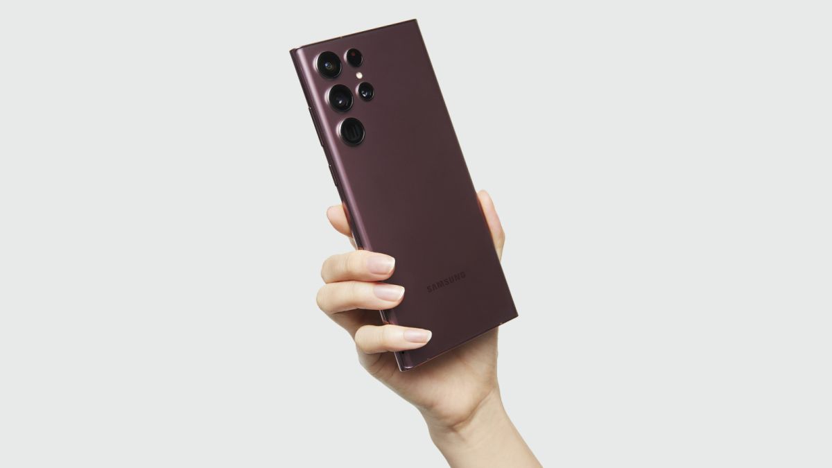 The Samsung Galaxy S22 Ultra in burgundy, held in a hand with the back showing