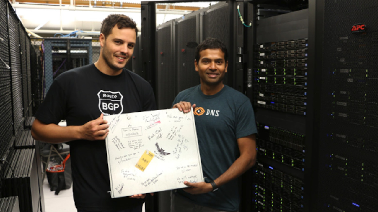 Mohit Lad and Ricardo Oliveira with ThousandEyes' first server, signed and covered in sticker tape.