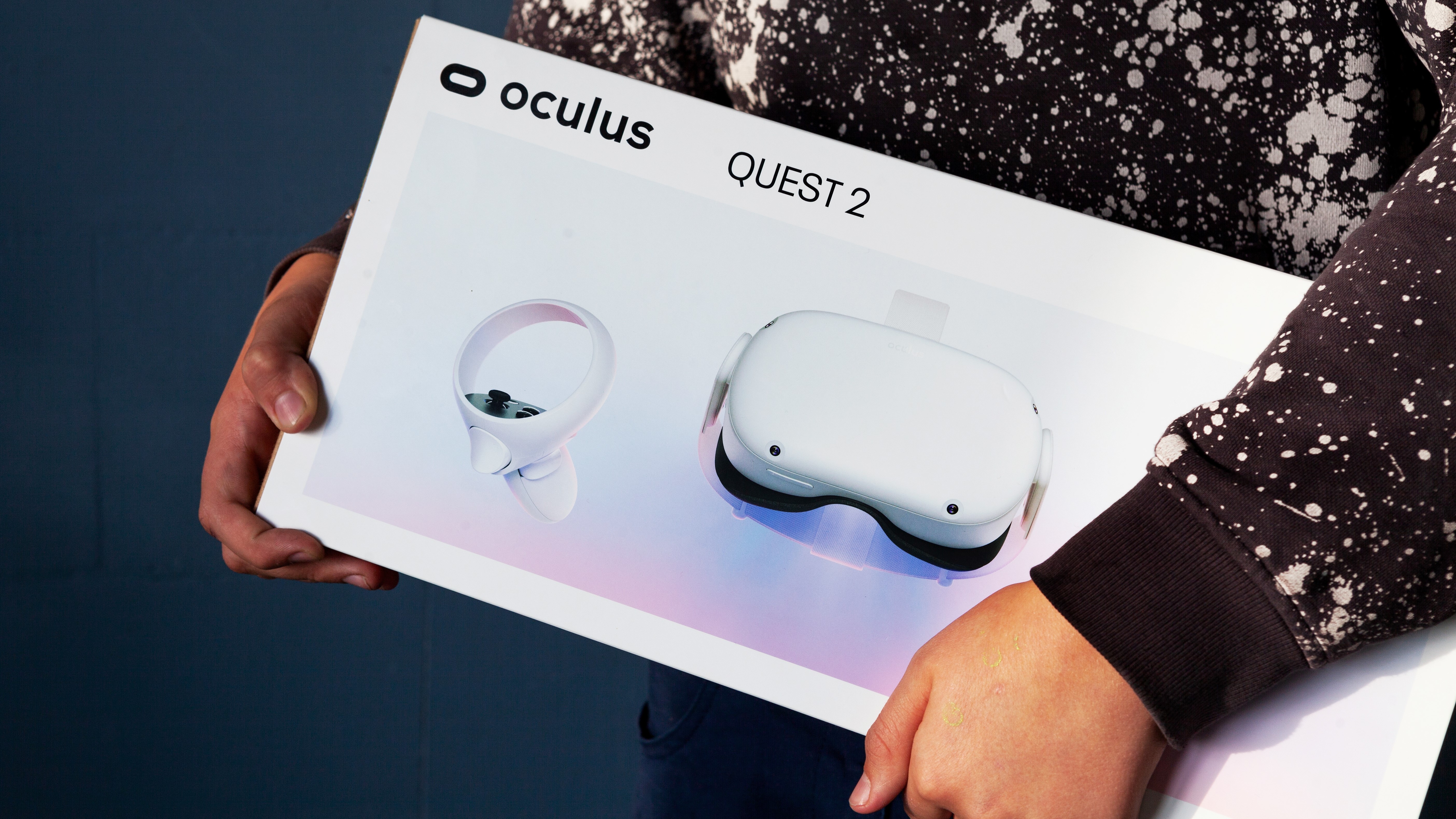 A person carrying a box with an Oculus Quest 2 VR headset in