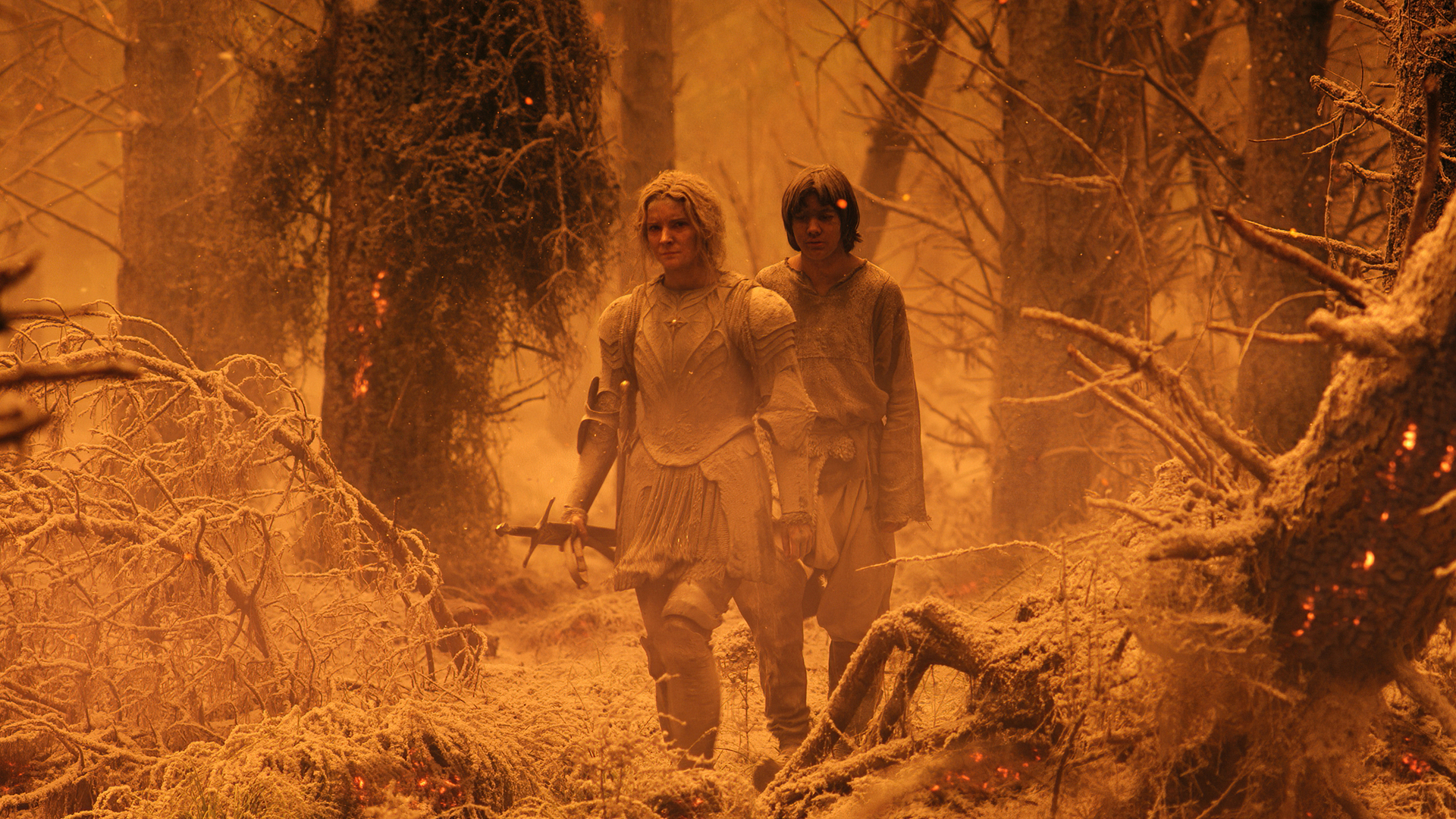An ash covered Galadriel and Theo walk through a fire-destroyed forest in The Rings of Power episode 7