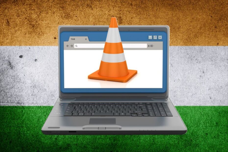 A laptop with a traffic cone coming out from the screen on the Indian flag on the background