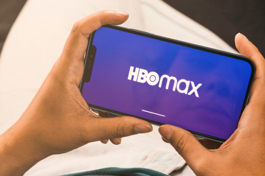 A person holds a smartphone with the HBO Max logo on it