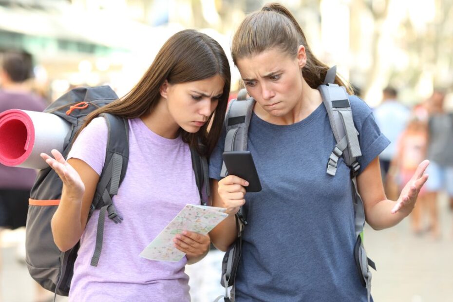 Two lost backpackers confused with gps location using a smart phone in the street